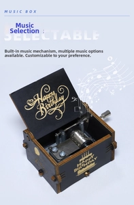 Detail of hand-cranked black wooden music box with golden Happy Birthday engraving