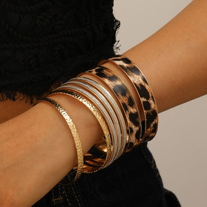 Close-up of stacked leopard print bracelets with gold hammered texture and glitter accents
