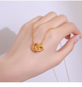 Close-up of interlocking gold heart necklace with sparkling zircon pavé on a model hand
