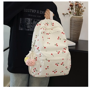 Corduroy cherry print backpack with plush cloud pendant shown on a model for scale