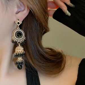 Detail of vintage bohemian tassel earrings with gold finish and black faceted gemstone beads