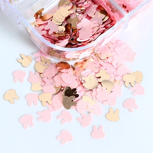 Macro shot of pink and gold bunny-shaped nail sequins and glitter for DIY craft decor