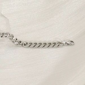 Close-up of titanium steel curb bracelet with lobster clasp on white glitter fabric