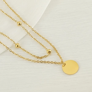 Detail of double-layer gold stainless steel necklace with coin pendant and beads