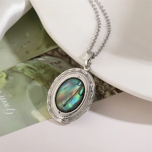 Macro shot of silver oval locket necklace with iridescent green abalone shell inlay