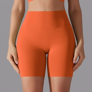 Detail view of high-waisted seamless orange yoga shorts with wide elastic waistband