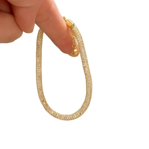 Golden mesh purse bracelet with zircon crystals held in hand on white background
