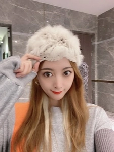 Close-up of white crochet knit hat with fluffy flower pattern on woman in selfie view