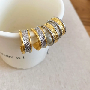 Macro detail of 18k gold-plated C-shape earrings with textured lava design and dual tones