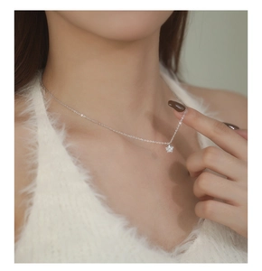 Close-up of minimalist silver star pendant necklace featuring zircon stones on a female model