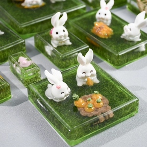 Detailed macro view of miniature resin rabbit figurines on a green moss base