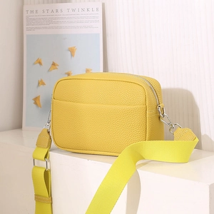 Detail of yellow lychee pattern leather crossbody bag with wide woven strap