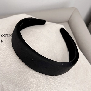 Detail of wide black headband with dotted texture resting on a beige fabric bag