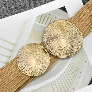 Detail of khaki woven summer belt with large gold round sunray texture metal buckle