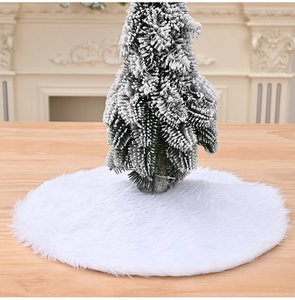 Detail of soft white faux fur Christmas tree skirt on a rustic wooden surface with small tree