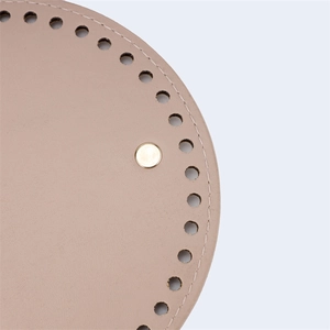 Close-up of 15cm round PU leather bag base with gold metal studs and stitching