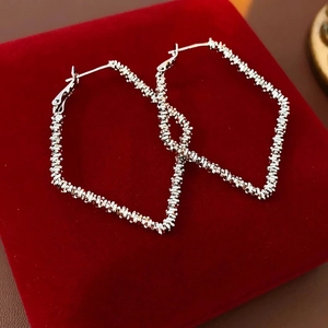 Silver geometric rhombus hoop earrings with textured finish on red velvet display