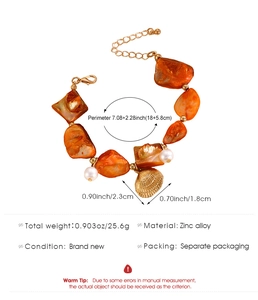 Dettaglio della collana con pietre arancioni, perle e ciondoli a conchiglia oro