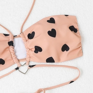 Détail macro d'une boucle en métal en forme de cœur sur un haut de bikini rose à pois