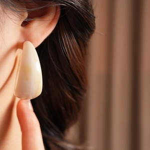 Detailed view of cream resin C-shaped earrings with a marbled vintage texture