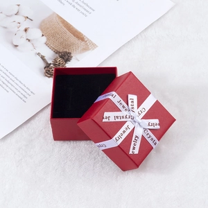 Detail of red square jewelry box with white ribbon and black velvet lining for rings