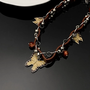 Detail of Y2K leather cord necklace featuring enamel butterfly and amber beads