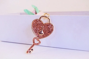 Macro shot of rose gold heart lock and key keychain set with sparkling pink rhinestones