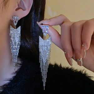 Close-up of sparkling silver triangle tassel earrings with rhinestones on a model
