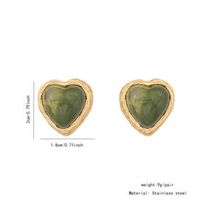 Macro detail of heart earrings with green gemstone in gold stainless steel frame