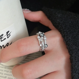 Detail shot of a triple-layer pearl ring with zircon accents on a model holding a cup