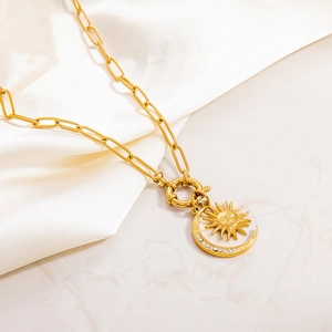 Detailed close-up of 18k gold celestial pendant necklace on white silk fabric background