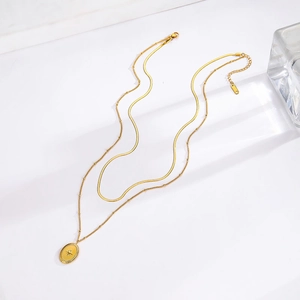 Double layered gold necklace with star pendant and snake chain on white background