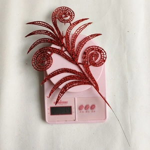 Close-up of sparkling red glitter Christmas leaf branch decoration on a scale weighing 14g