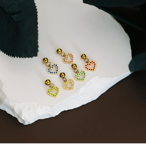 Detailed view of six colorful rhinestone heart pendants on a textured white stone