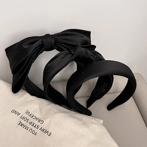 Detail showing two black satin headbands with white polka dots and elegant bow design
