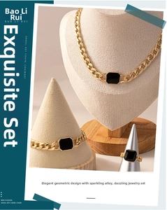 Detail shot of gold Cuban link jewelry set with black geometric squares on display