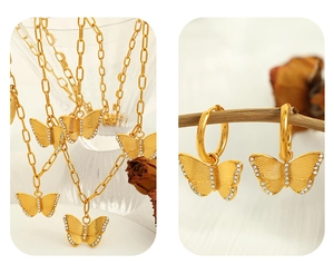 Macro shot of gold butterfly necklace and earrings set with white zircon details