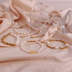 Detail of luxury pearl and gold cuban chain jewelry set on silk background