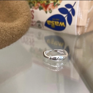 Detailed macro view of an S925 sterling silver wavy ring with Smile engraving and reflection