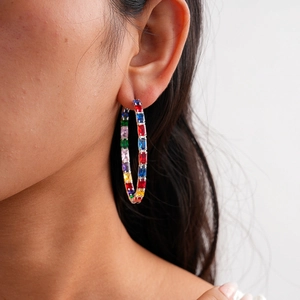 Macro shot of silver hoop earrings with multicolored rectangular cubic zirconia gems