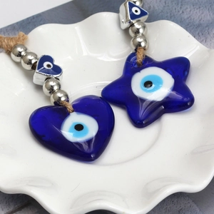 Detail of blue evil eye heart and star pendants with jute rope and metallic beads