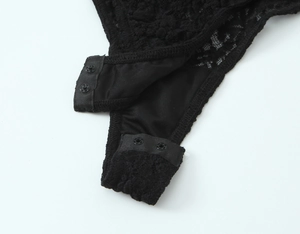Detailed close-up of the snap button closure and black lace fabric on the bodysuit