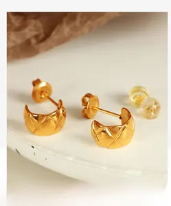 Macro shot of gold-plated C-shaped earrings with quilted texture and double backing