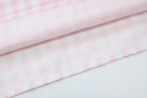 Detailed close-up of pink and white plaid fabric with professional hem stitching