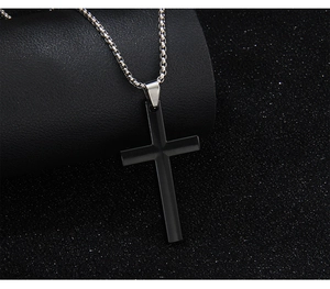 Close-up of a minimalist black stainless steel cross pendant on a silver box chain