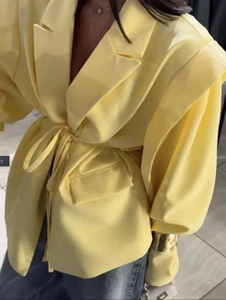 Detail eines hellgelben Blazers mit gepolsterten Puffärmeln und Taillenschnürung Design