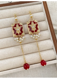 Macro detail of vintage red enamel earrings with gold floral relief and pearls