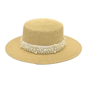 Détail du chapeau de soleil en paille tressée avec ruban élégant orné de perles blanches