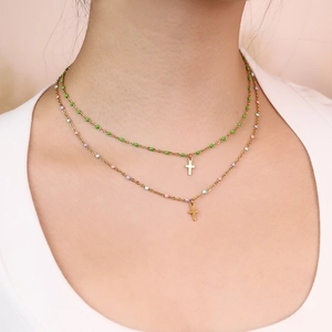 Close-up of double layered gold cross necklace with pastel beads on a female model