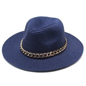 Detailed close-up of navy blue woven straw hat featuring a luxury gold metal chain decoration